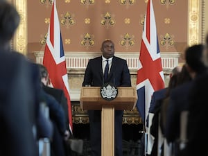 Foreign Secretary David Lammy delivering a speech at lectern with Union flags at either side