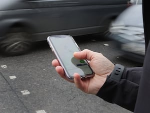 A person using their phone at a pedestrian crossing