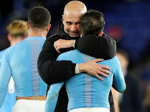 Manchester City manager Pep Guardiola, centre left, embraces Bernardo Silva following victory at Leicester