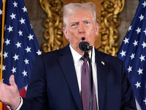 President-elect Donald Trump speaking into a microphone with US flags in background