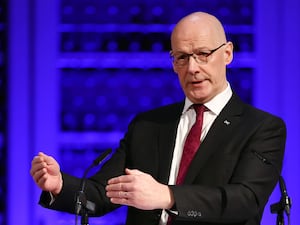 John Swinney gesturing with his hands while speaking