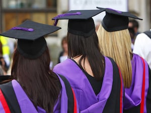 The backs of three students in graduation gowns and hats