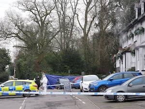 Police vehicles, tape and a forensic tent set up outside