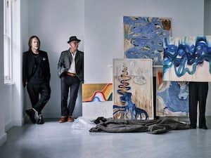 Two men standing near a series of blue paintings