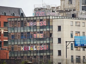 Derelict office building with graffiti saying house the homeless