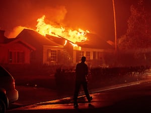 A firefighter walks toward a burning structure