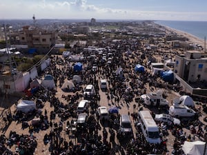 Palestinians gather with their belongings near a roadblock as they wait to return to their homes in the northern part of the Gaza Strip