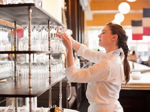 A waitress stacking wine glasses in a restaurant