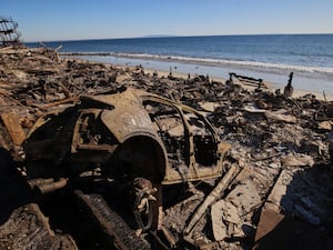 A burned car is seen among debris in the wreckage of a home destroyed by the Palisades Fire in Malibu