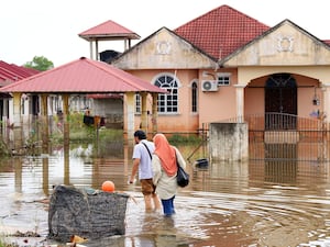 People wade through floodwater in Tumpat, on the outskirts of Kota Bahru, Malaysia