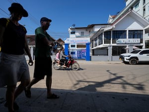 Foreign tourists walk past the closed Nana Backpackers hostel in Vang Vieng