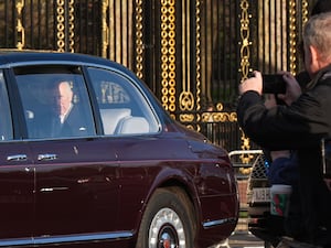 A man photographs the arrival of the King's car