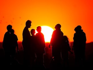 People silhouetted in front of the setting sun