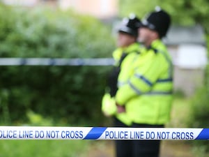 Police officers stand beside a crime scene cordon