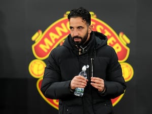 Manchester United manager Ruben Amorim standing in front of the club crest