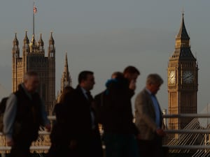 Commuters walking over a bridge with Big Ben in the background