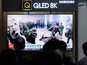 A TV screen shows an image of soldiers believed to be from North Korea stand in line to receive supplies from Russia