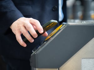 Someone travelling by train taps their phone on a reader