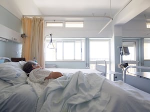 Elderly woman lying on her bed in a hospital ward