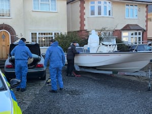 Forensic officers carry out searches of a boat and car on the driveway of a house in Poole