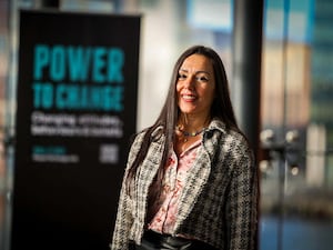 Woman stands in front of a banner with the words 'power to change' on them