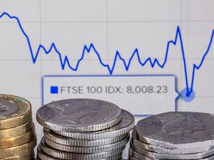 Coins in front of a FTSE 100 graph