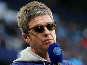 Noel Gallagher speaking into a microphone