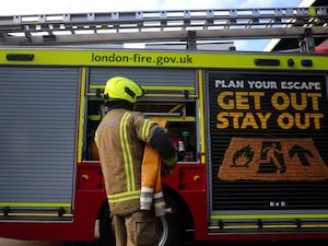 A firefighter holding a hose on a fire engine