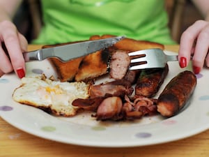 A plate of fried food, consisting of a fried slice, an egg, bacon rashers and sausages