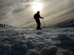 Person skiing over snowy landscape with a low winter sun behind them