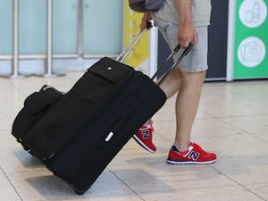 A passenger at an airport pulling a suitcase