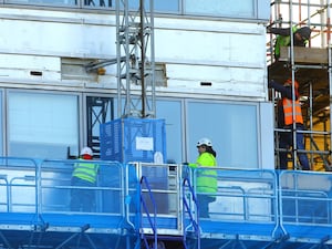 Workers remove the cladding from the facade of a block of flats