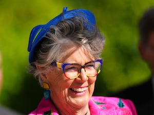 Dame Prue Leith smiling, wearing blue hat and pink blazer