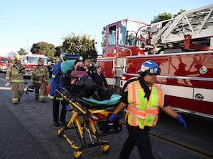 A woman is carried on a stretcher near the site of a plane crash