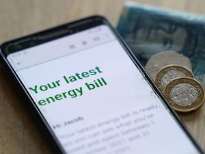 Cash next to a smartphone displaying an energy bill