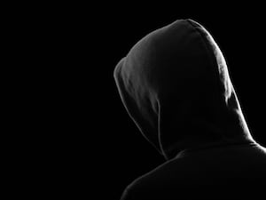 A silhouette of a male youth in a hoodie