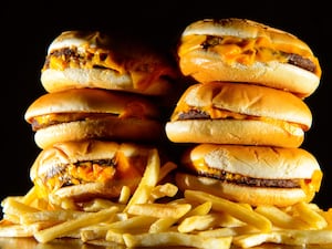 A generic stock photo shows a pile of cheeseburgers and French fries