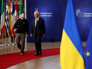 Volodymyr Zelensky, left, speaks to European Council president Antonio Costa as they arrive for an EU summit, with flags in the foreground