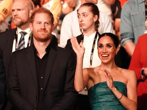 The Duke and Duchess of Sussex with Meghan waving surrounded by people