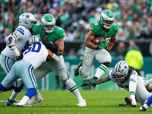 Philadelphia Eagles running back Saquon Barkley, center, leaps as Dallas Cowboys linebacker Marist Liufau tries to trip him up