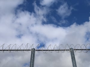 A prison fence with blue sky behind