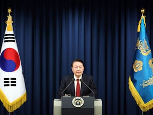 South Korean president Yoon Suk Yeol delivers a televised address, flanked by two flags