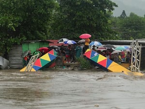 People stand at a collapsed pedestrian bridge at a river in Honduras