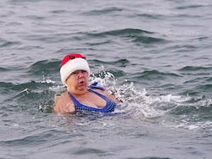 A woman in a Christmas hat swimming in the sea