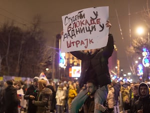 Protesters hold a banner reading “Students to the blockades, workers to strike” in Serbian Cyrillic as they gather outside Serbia’s state television building