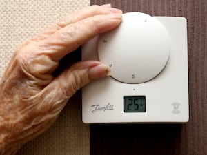 An elderly person's hand adjusting a thermostat