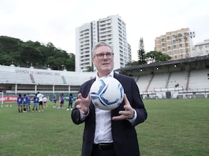 Sir Keir Starmer holding a football on a pitch