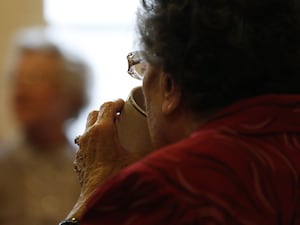 An elderly woman drinking from a mug