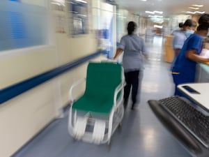 A nurse moves a hospital wheelchair across a corridor