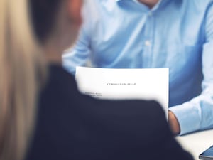 A woman reading a CV sitting opposite another person in a shirt